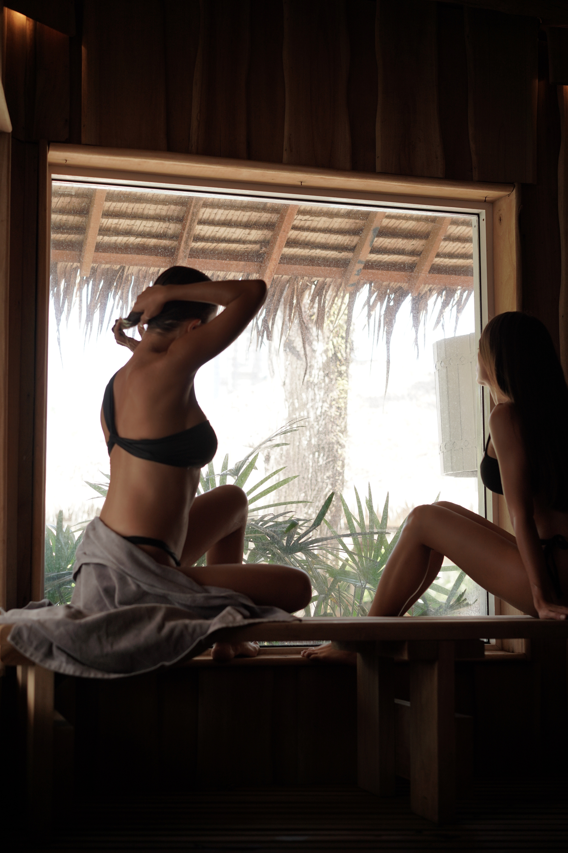 Guests in peaceful contemplation inside the Finnish sauna at Maji, overlooking tropical garden